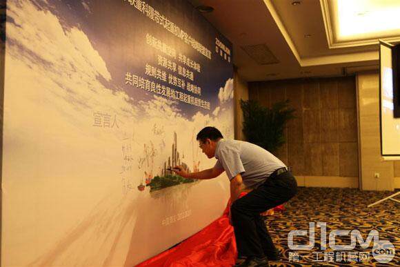 与会代表在签名墙上纷纷签名，图为中联工起公司总经理熊焰明正在签名。