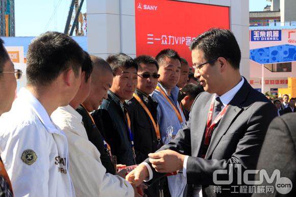三一重工副总裁 向儒安，与客户代表们握手致意，并赠送三一挖掘机模型