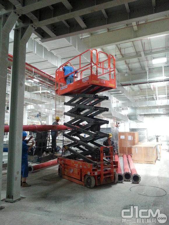 工人们正在使用剪叉式高空作业平台进行管道安装