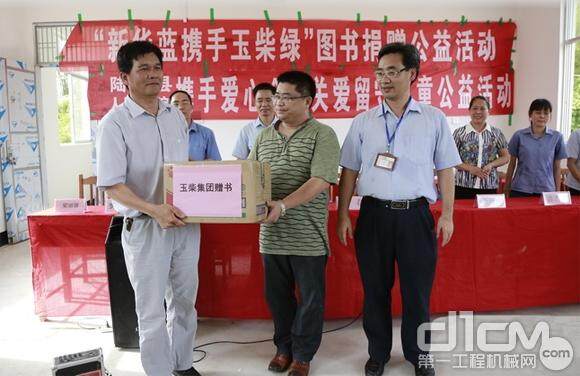 陆河小学校长罗济焕（左）代表校方从郭德明（右）、庞春（中）手中接过捐赠书籍