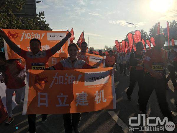 志愿者们在跑步过程中拉起印有日立建机字样的小旗，为参赛者加油助威