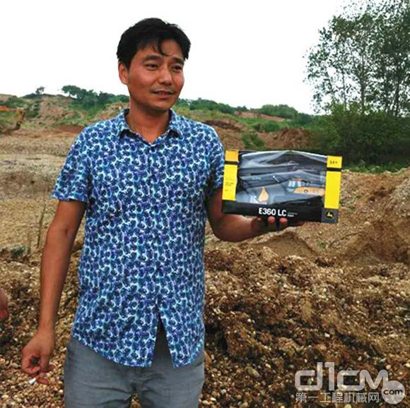 王天元手中拿着一台约翰迪尔挖掘机模型