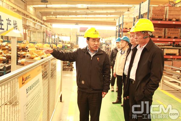 山东临工总经理文德刚（左一）向岚桥集团副总裁叶勇（右一）介绍生产现场