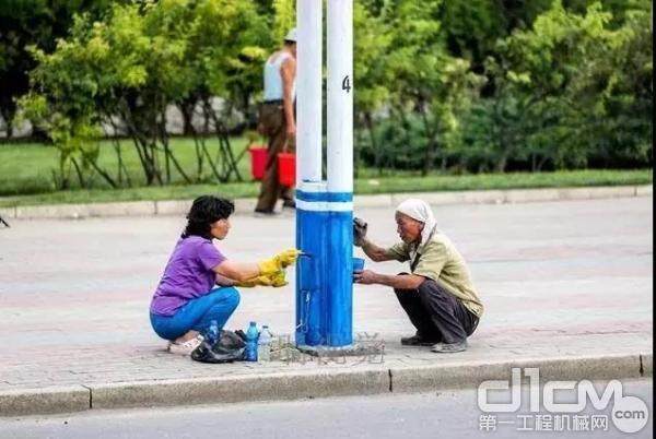 环卫工人在清理路灯杆上的脏污 