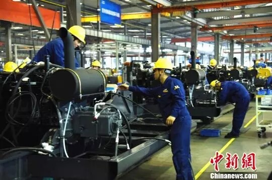 图为技术工人在整洁的厂房中进行“人机配合”，高效率生产机器。朱志庚 摄