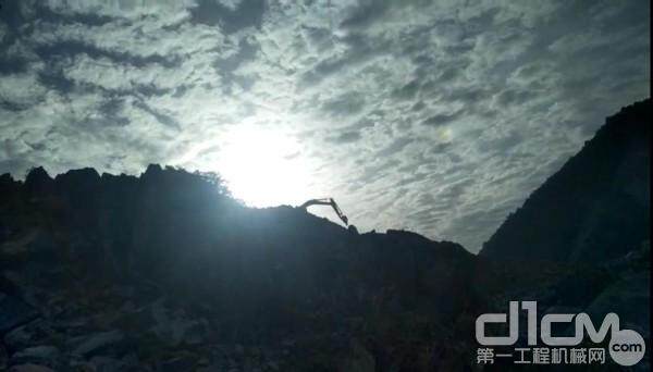 一张清晨拍摄的小松挖掘机在矿山山顶施工的图片。