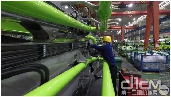 2月14日 在经过消毒防疫的车间里，中联重科一名戴着口罩的工人正在组装泵车产品
